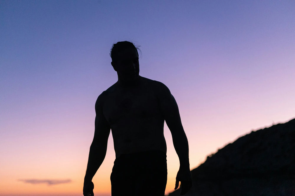 Silhouette of a male against a colorful sunset sky outdoors representing testosterone replacement therapy for men